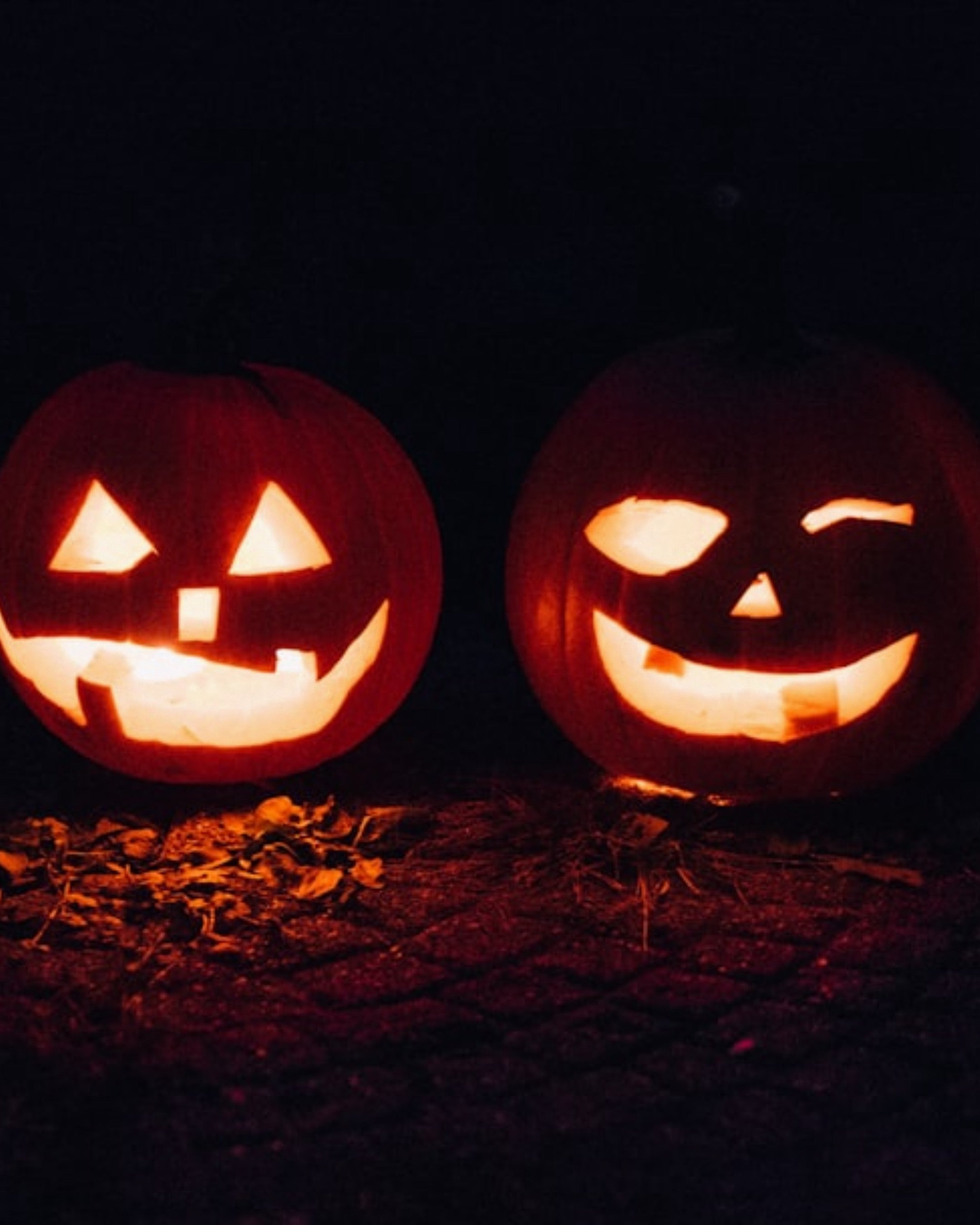Two cut pumpkins glowing at night