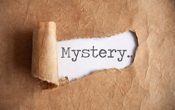Image of brown paper ripped back to reveal "Mystery." typed on white paper.