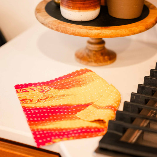 Decorative items including a candle, potted plant, and colorful towel on a surface.