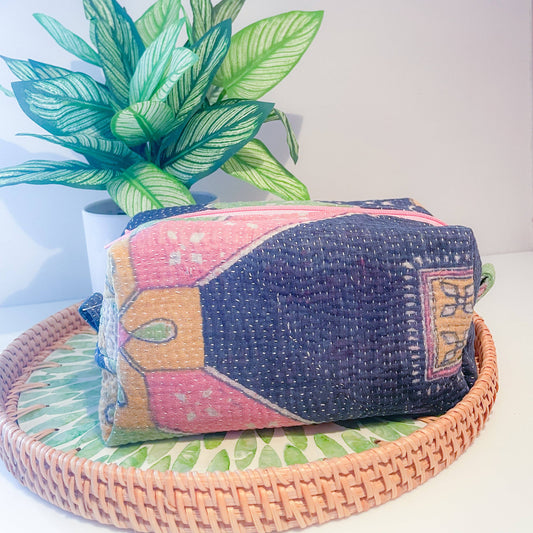 Colorful patterned zipper box pouch on a woven tray with a plant in the background