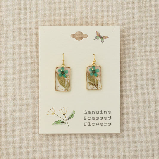 Pair of earrings with pressed flowers on a card labeled 'Genuine Pressed Flowers'