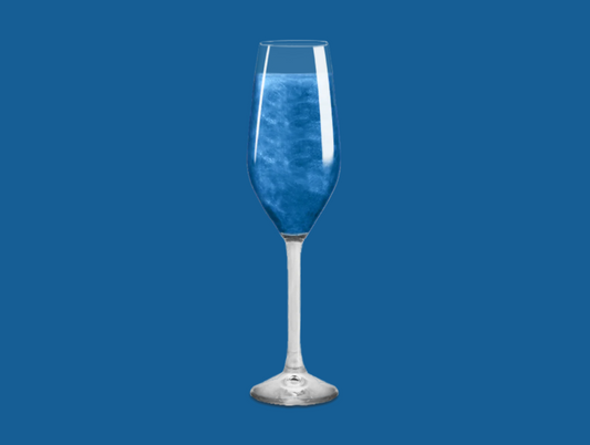 Blue Glitter Bomb dissolving in a champagne flute, turning the drink into a dazzling, colorful creation.