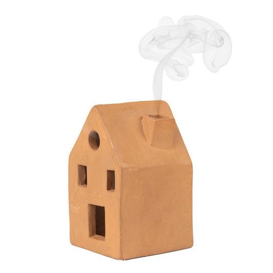 Terracotta incense holder shaped like a home with incense smoke comes from the chimney with a white background