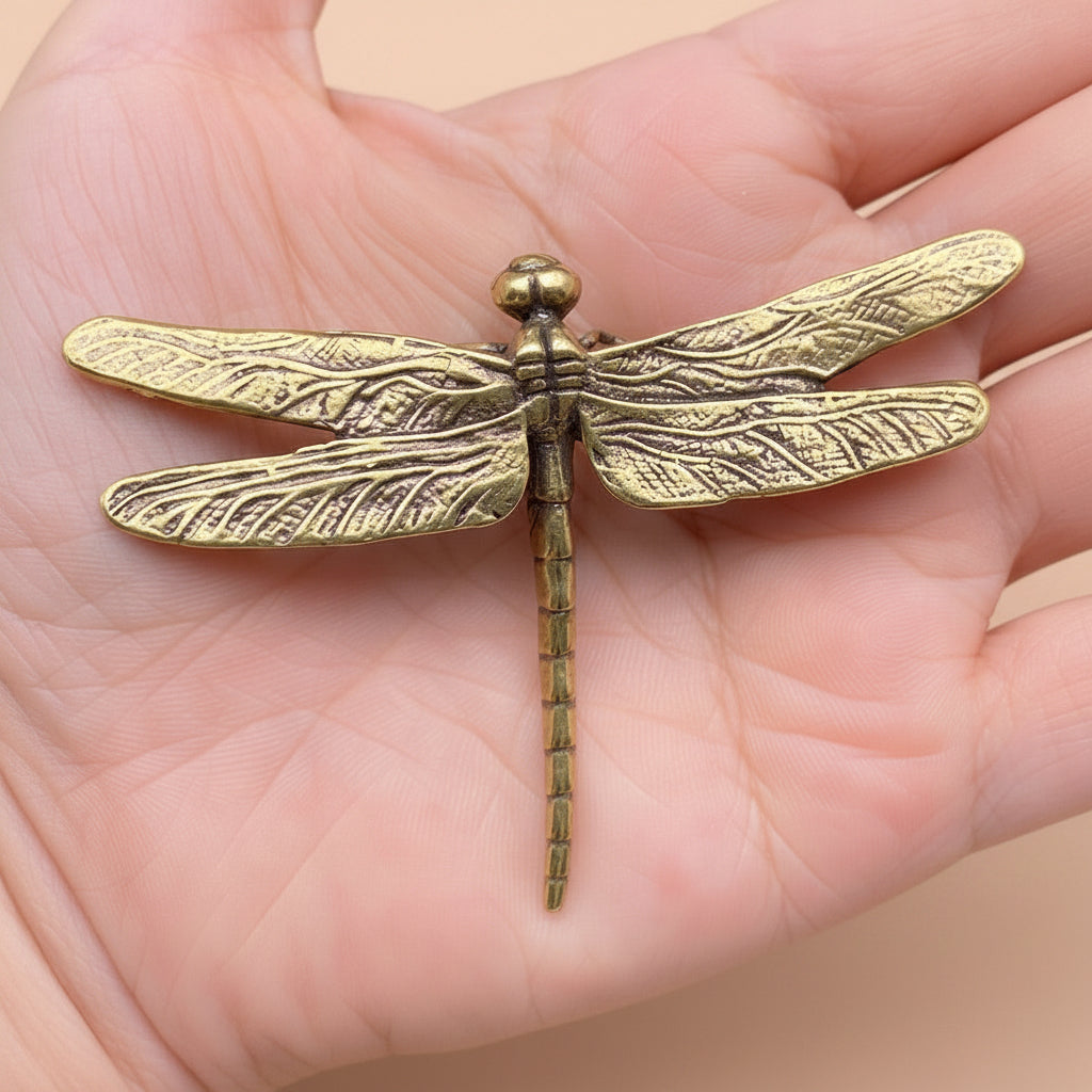 Gold dragonfly-shaped object held in a hand
