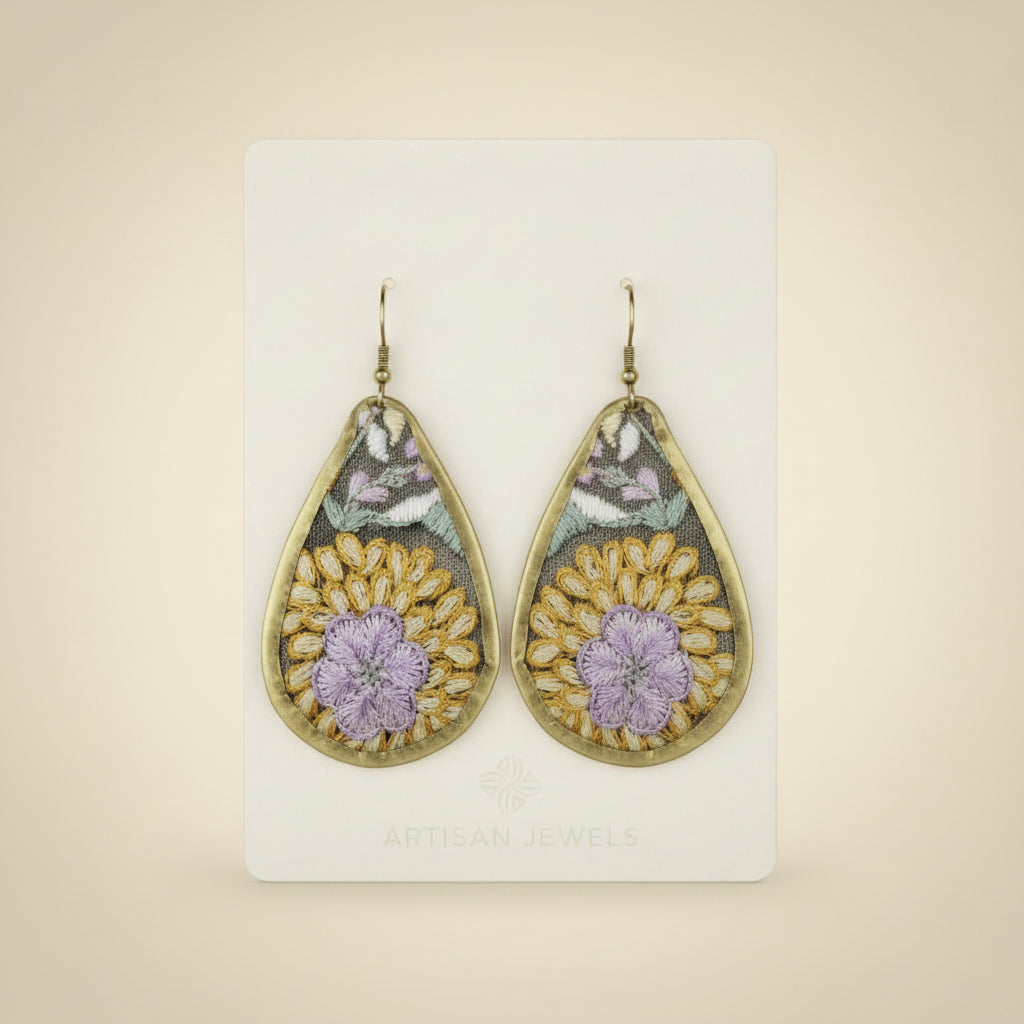 Teardrop-shaped earring with floral design shown on a backing card on a white background