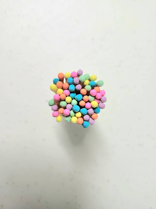 Close up of the colorful neon matchsticks in a corked glass vial.