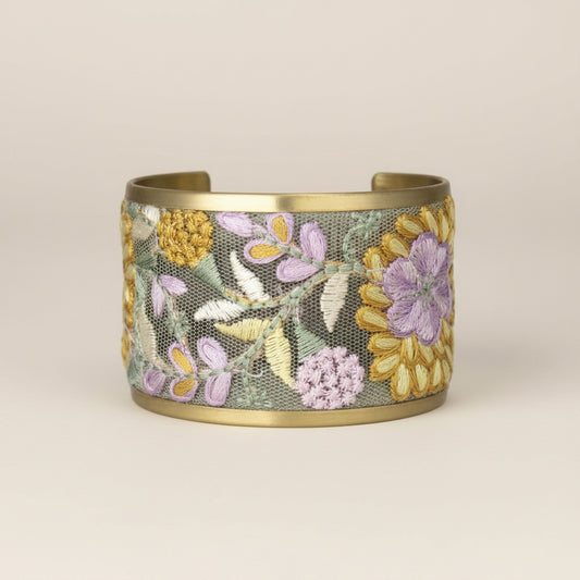 Gold bracelet with floral embroidery on a white background