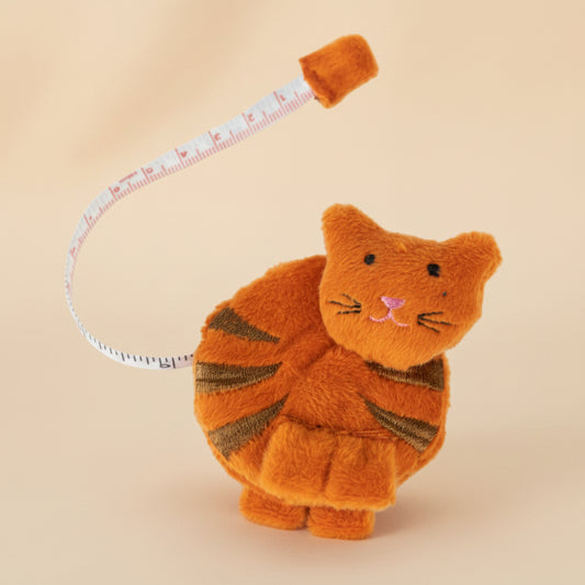 An orange fabric cat tape measurer on a white background