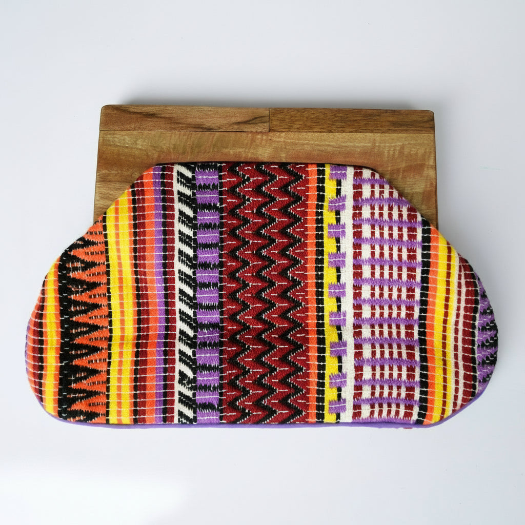 Colorful patterned clutch bag on a wooden block against a white background