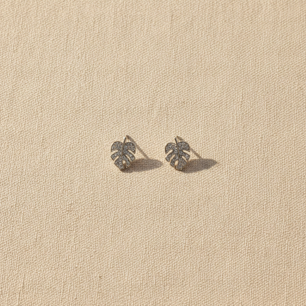 Monstera leaf earrings on a textured beige background from Rochambeau Home