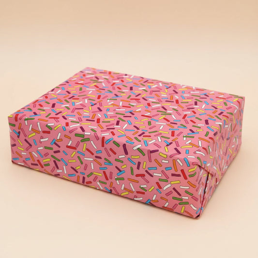 Rectangular box with pink sprinkles pattern wrapping paper on a gift and on a light beige background