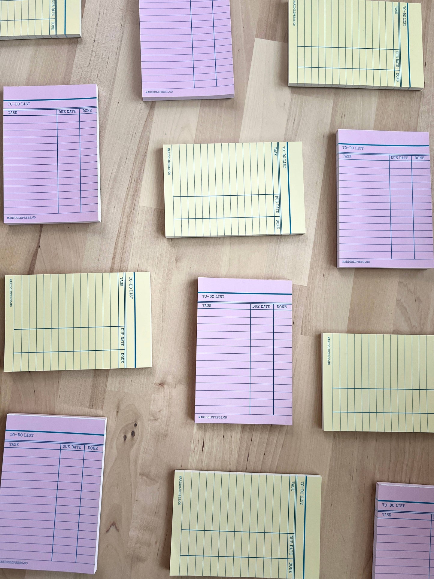 Pink and Yellow Library Card Notepads lined up on a rustic table