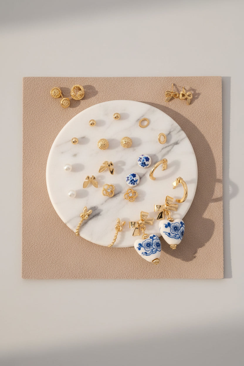 A collection of ceramic earrings with pearl and ribbon bow designs displayed on a round white surface.