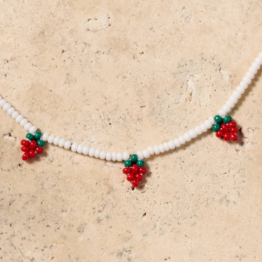 Adjustable strawberry necklace with bright beadwork, glowing white beads on soft cotton string