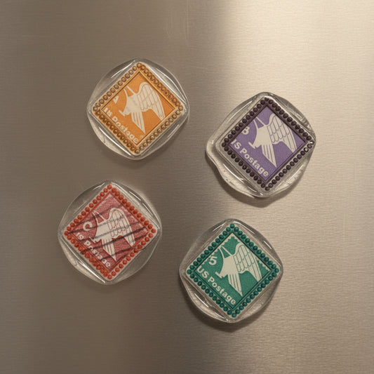 Four vintage-style postage stamp magnets created by Rochambeau Home by stamping in clear wax and multi-color gilding wax to showcase the details.