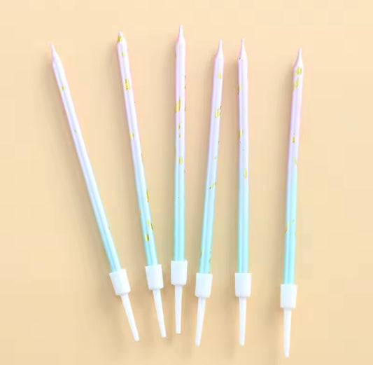 Long pastel candles with gold accents arranged next to mermaid-themed decor