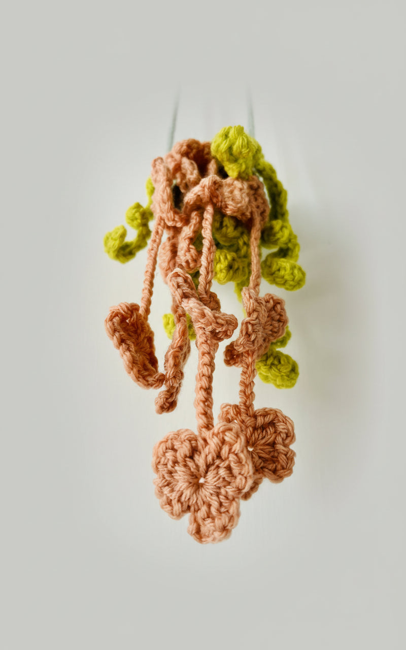 Botanical-inspired fiber art plant with gentle, heart-shaped leaves cascading from crocheted strands.