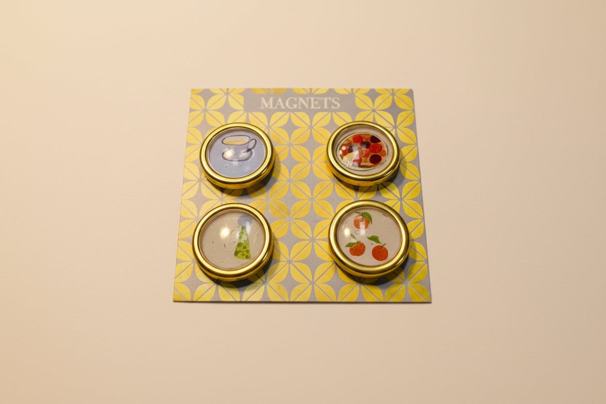 A set of handcrafted magnets by Rochambeau Home feature a tea cup, party hat, fruit tart, and tangerine wax seal magnets for fridge or office