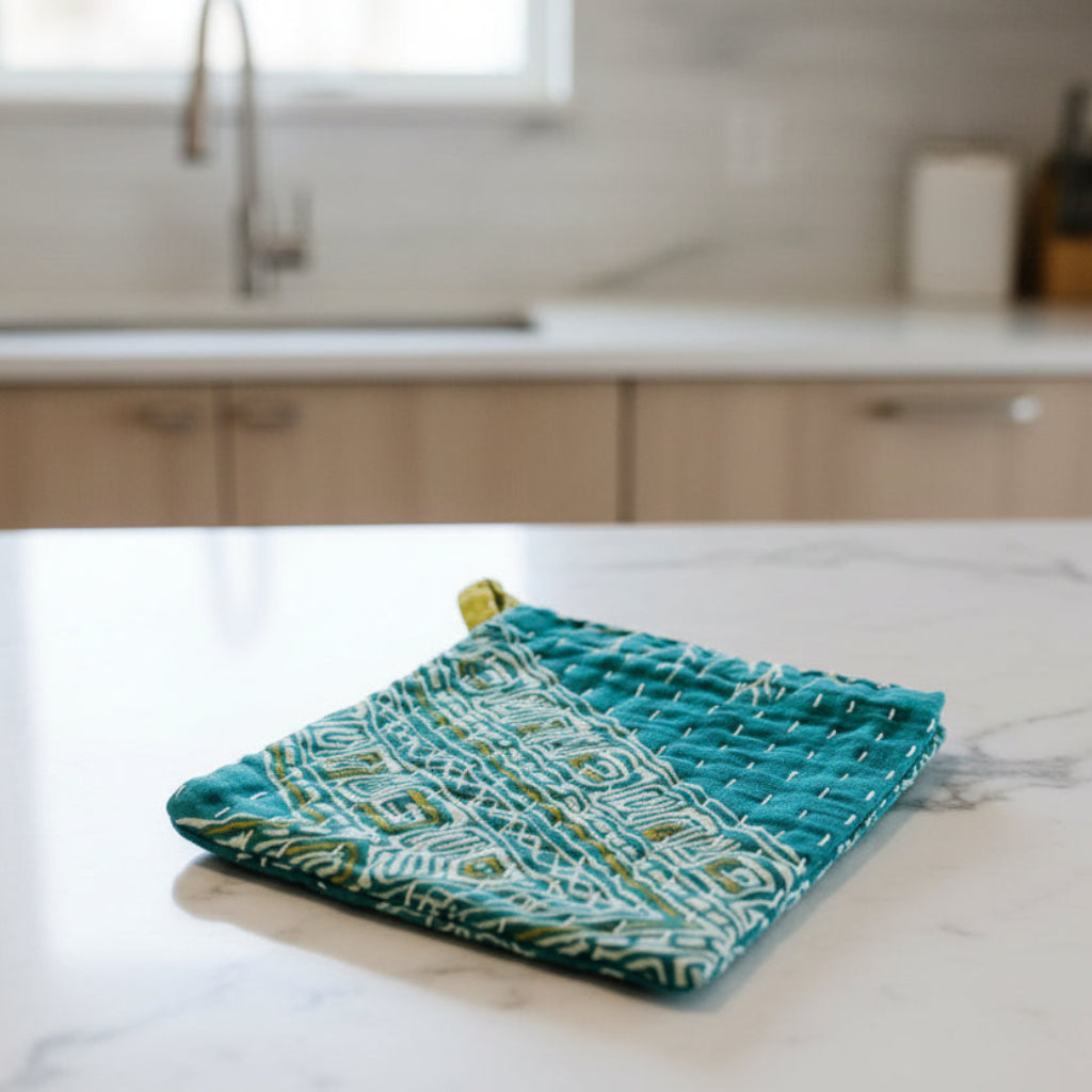 Teal fabric dish cloth with geometric pattern on a light gray background
