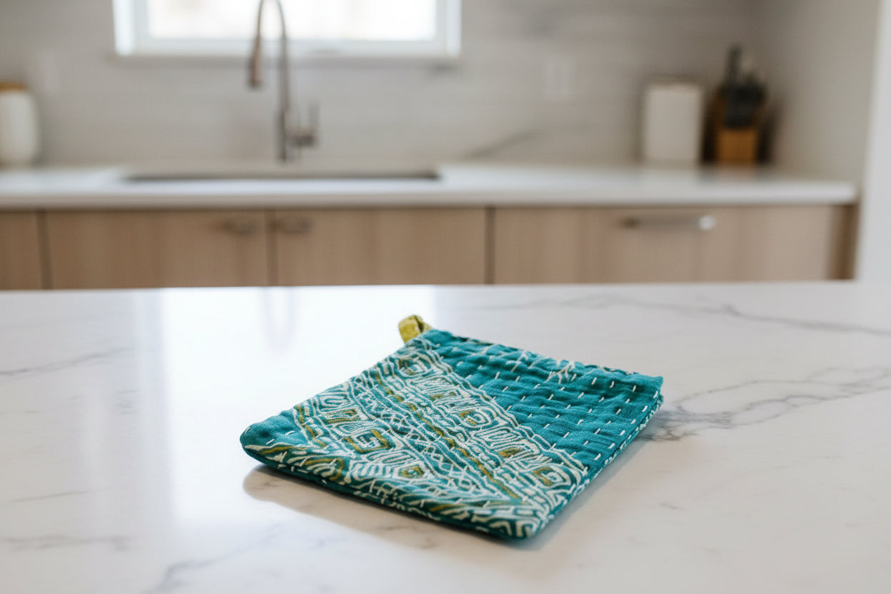 Teal fabric dish cloth with geometric pattern on a light gray background