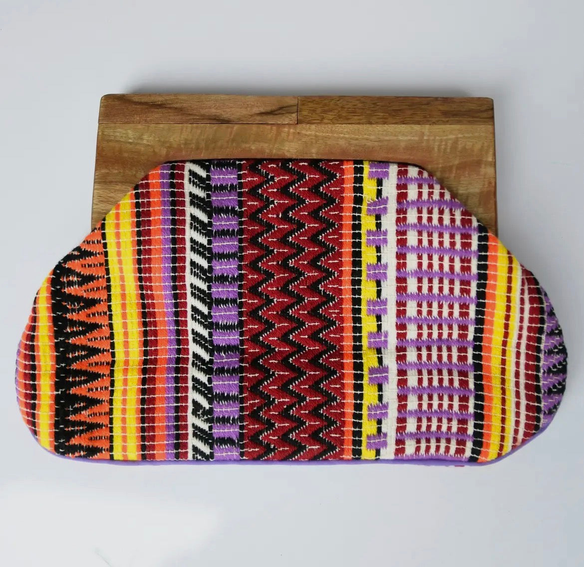 Colorful patterned pouch on a wooden block against a white background
