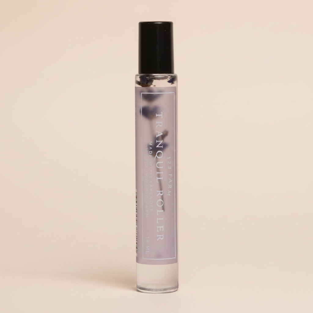 Small lavender glass roller bottle with black cap on a light gray background