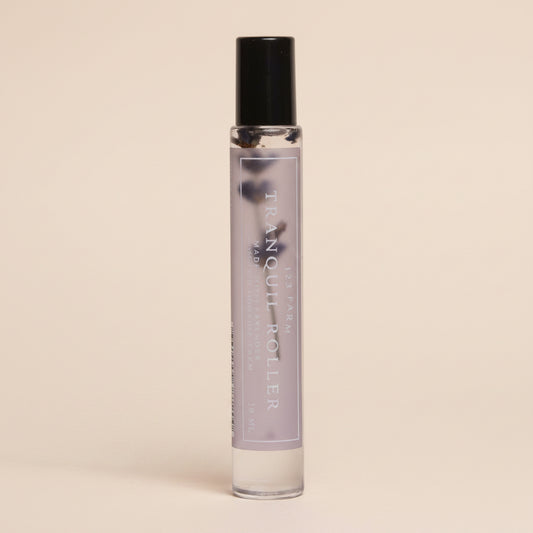 Small lavender glass roller bottle with black cap on a light gray background