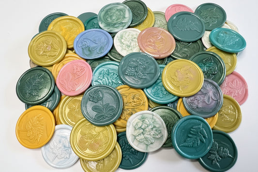 Garden-inspired wax seal stickers in shades of green, yellow, pink, and blue arranged on white stationery