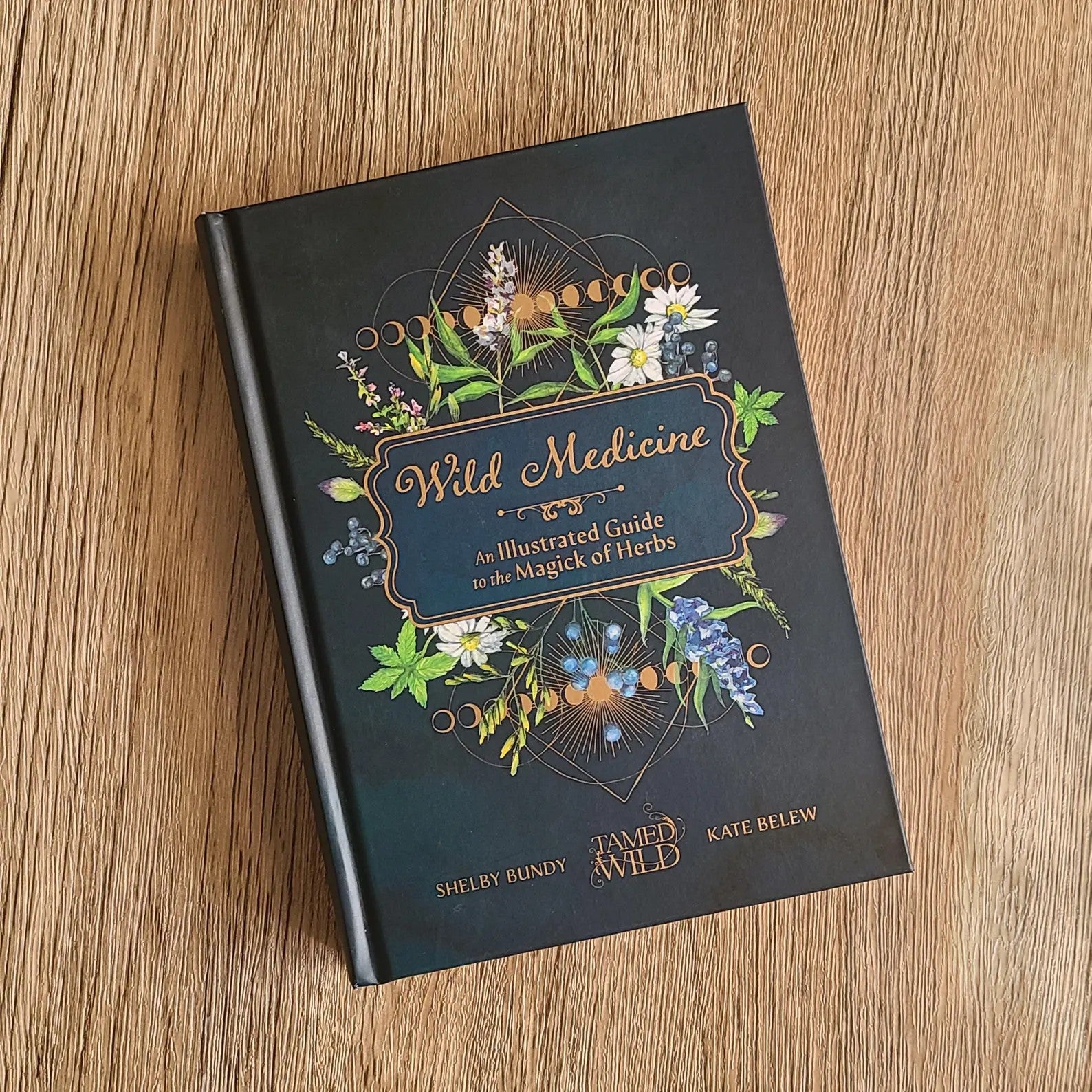 Book titled 'Wild Medicine' with floral design on a wooden surface