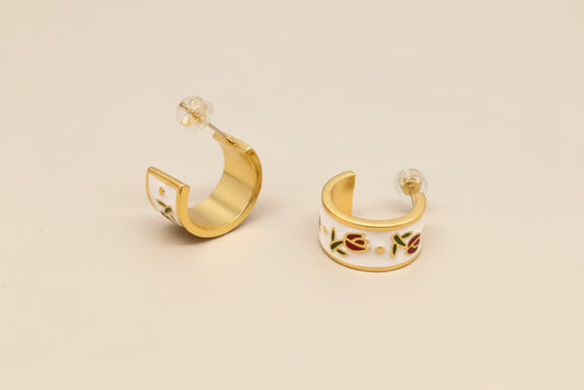 Gold hoop earrings with colorful designs on a gray background