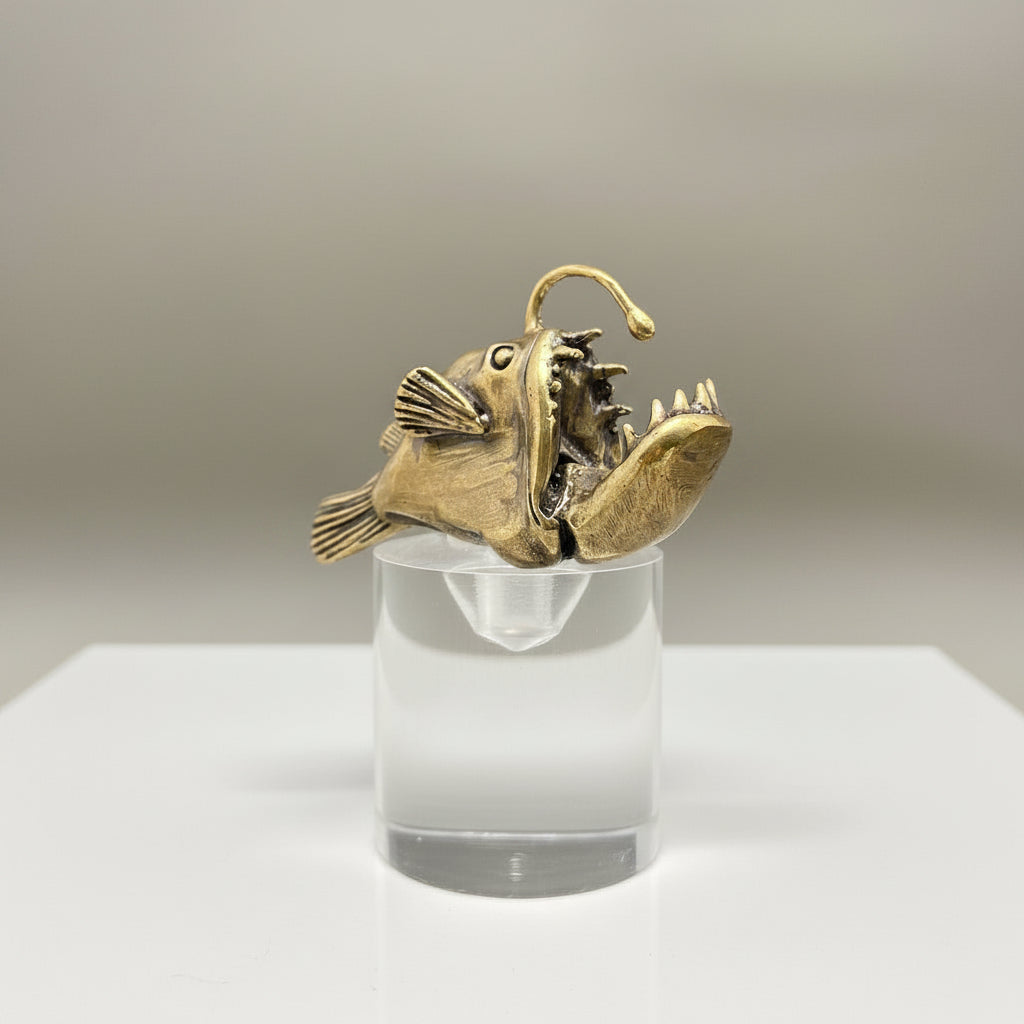 Bronze anglerfish sculpture on a clear stand against a gray background