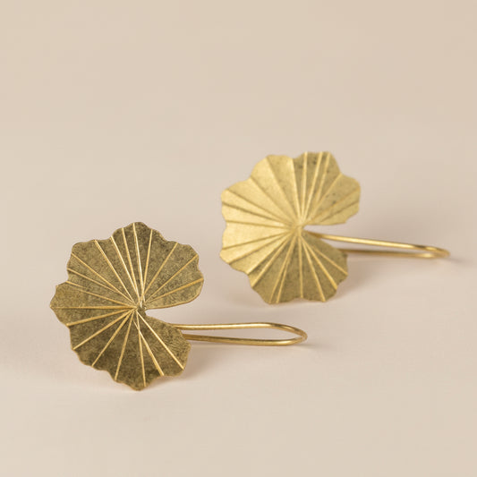 Pair of gold leaf-shaped earrings on a light gray background