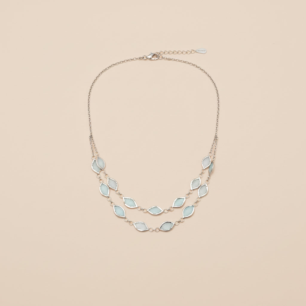 Necklace with light blue gemstones worn by a person against a neutral background