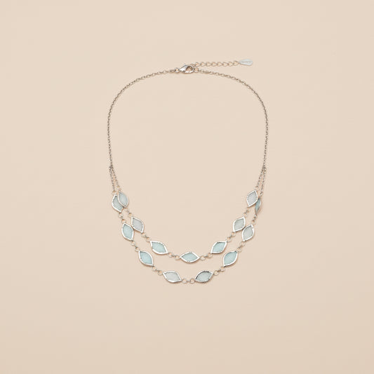 Necklace with light blue gemstones worn by a person against a neutral background