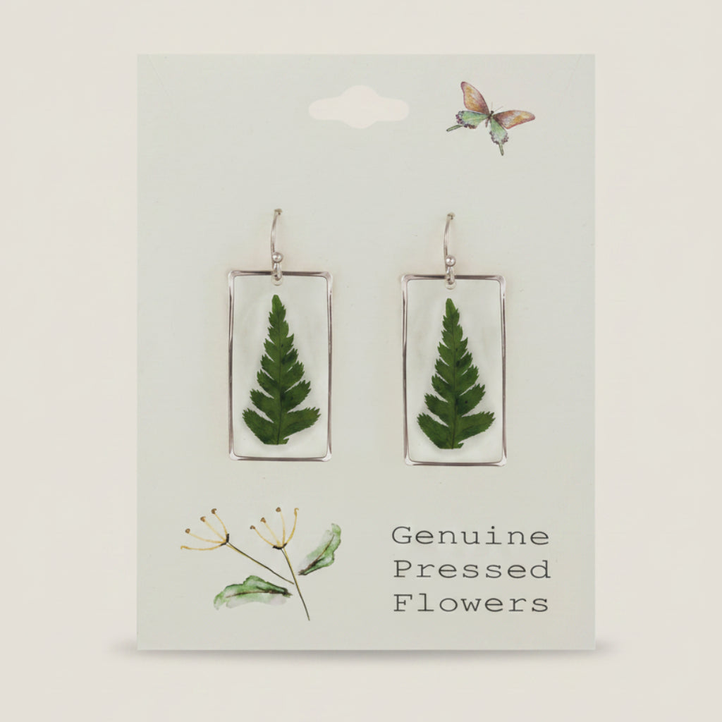 Earrings with pressed fern leaves on a card labeled 'Genuine Pressed Flowers'.
