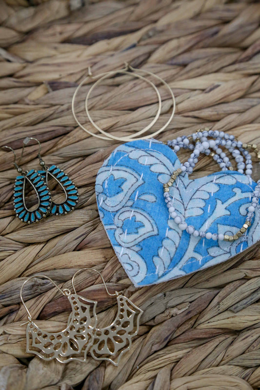 Set of earrings on a blue heart-shaped gift pouch with a woven background