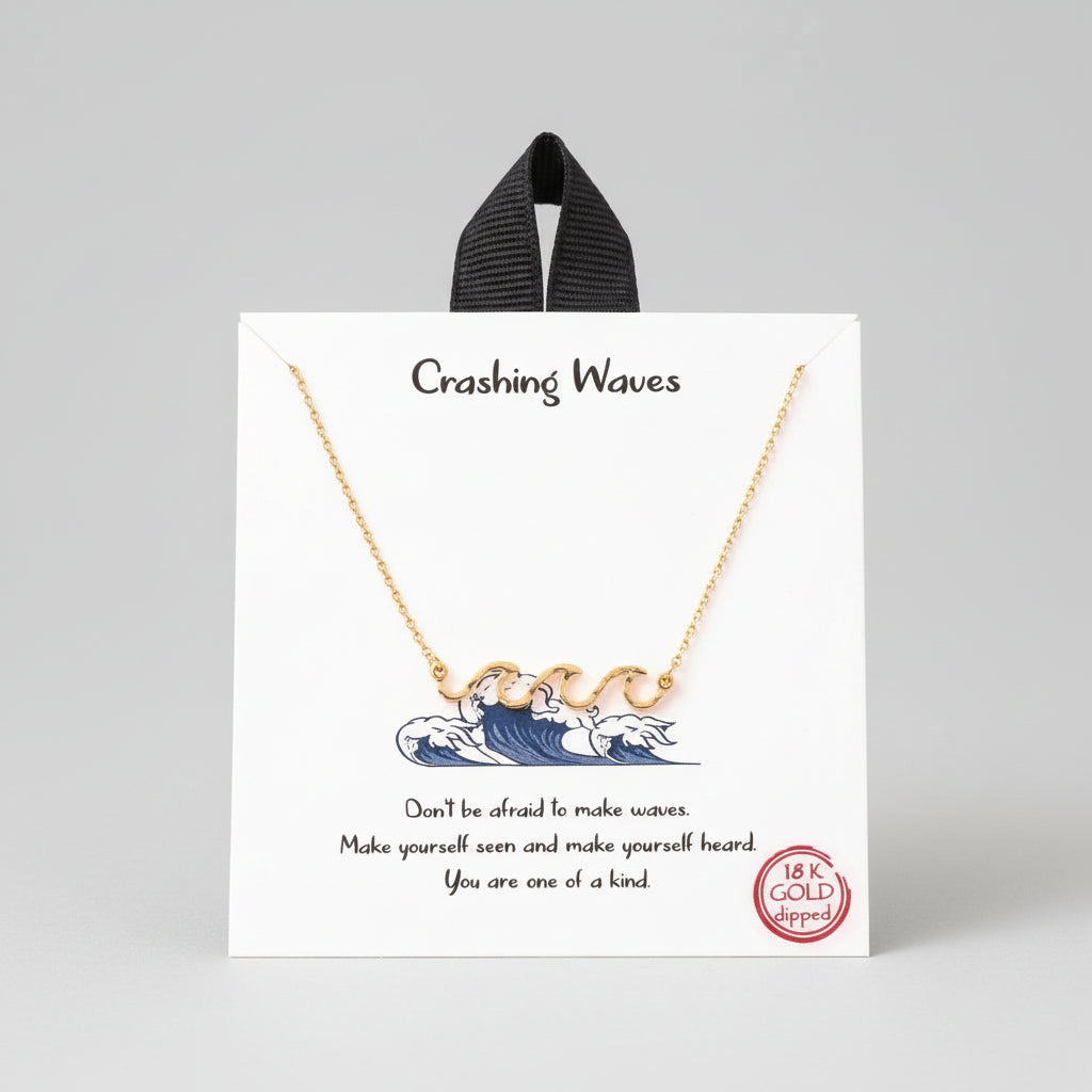 A gold-colored pendant necklace with a wave design, presented on a card that reads 'Crashing Waves' and includes a motivational message.