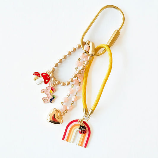 Rainbow bag charm keychain with pink beads, unicorn, and heart against white background