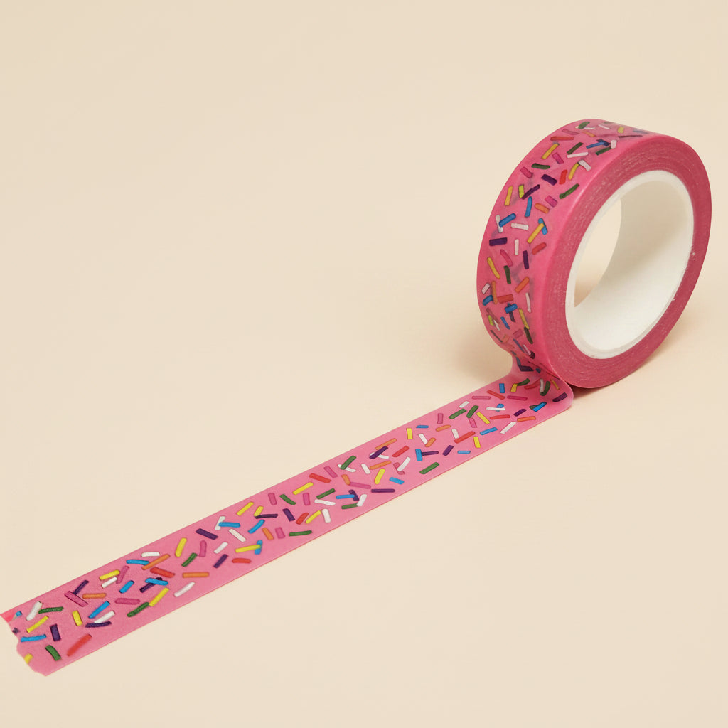 Roll of bright pink washi tape with multi-color sprinkles on a white background
