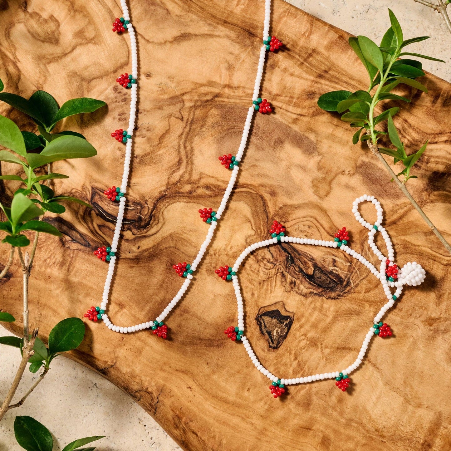 Artisan-crafted strawberry-themed bracelet with bright red and green beads against a neutral background