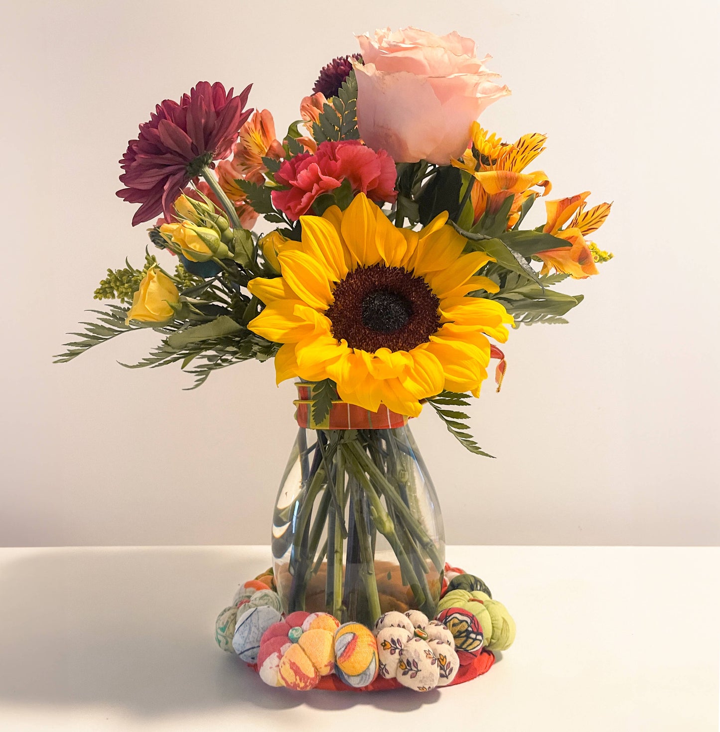 Bouquet of flowers in a clear vase on a white surface with a white background