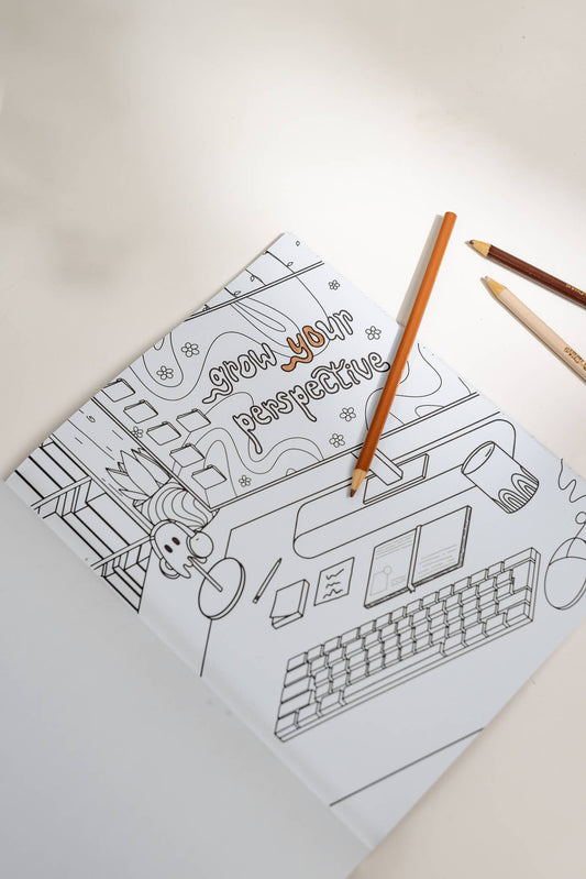 Coloring book with a design of a computer and text on a light surface with colored pencils.