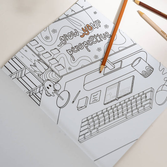 Coloring book with a design of a computer and text on a light surface with colored pencils.