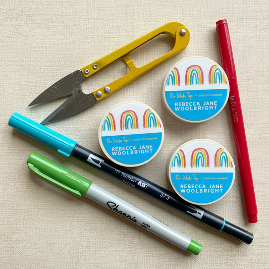 Roll of Over the Rainbow Washi Tape with label, next to scissors and stationery supplies