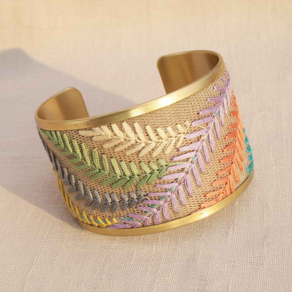 Decorative bracelet from Rochambeau Home with embroidered patterns on a textured surface with a neutral background