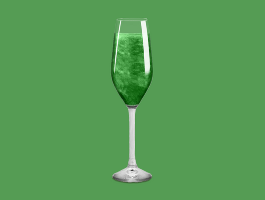 Green Glitter Bomb in a champagne flute, creating a dazzling green and glittery effect in the drink.