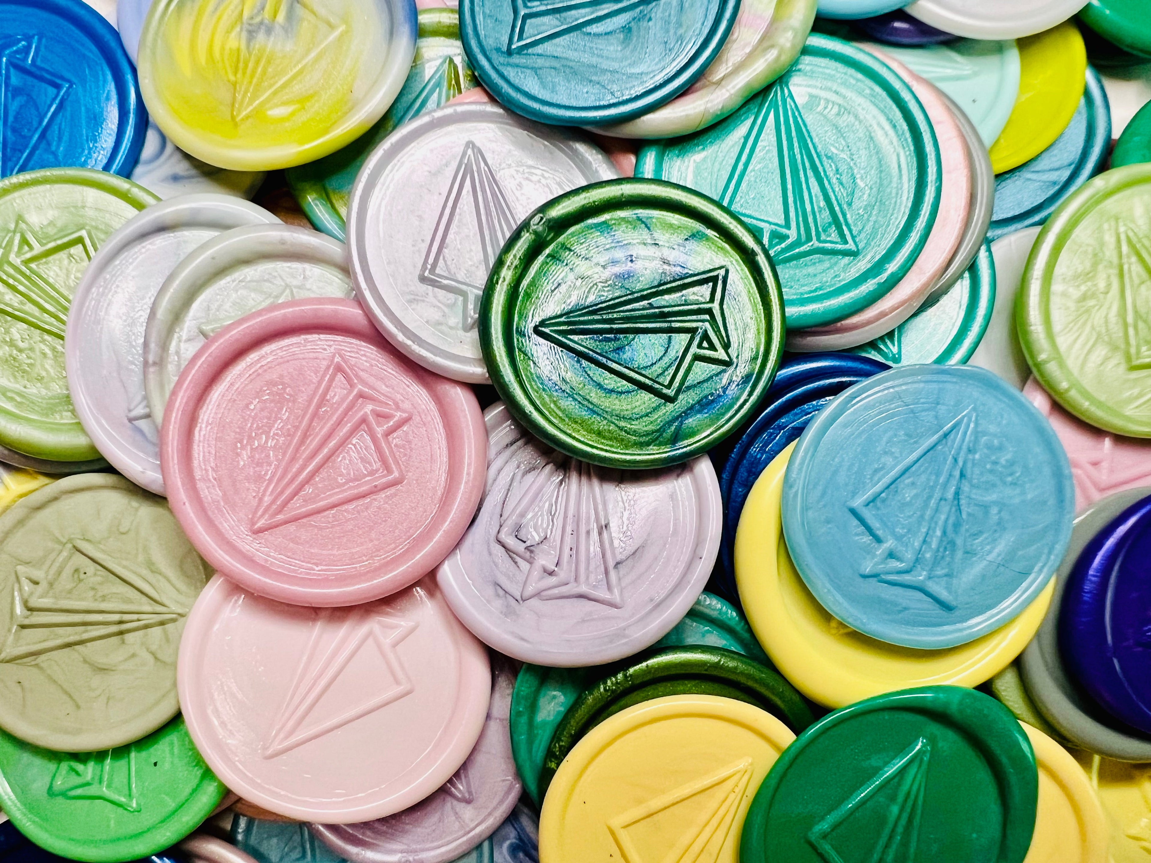 Close up image of a pile of Flight of Fancy wax seal stickers in various colors