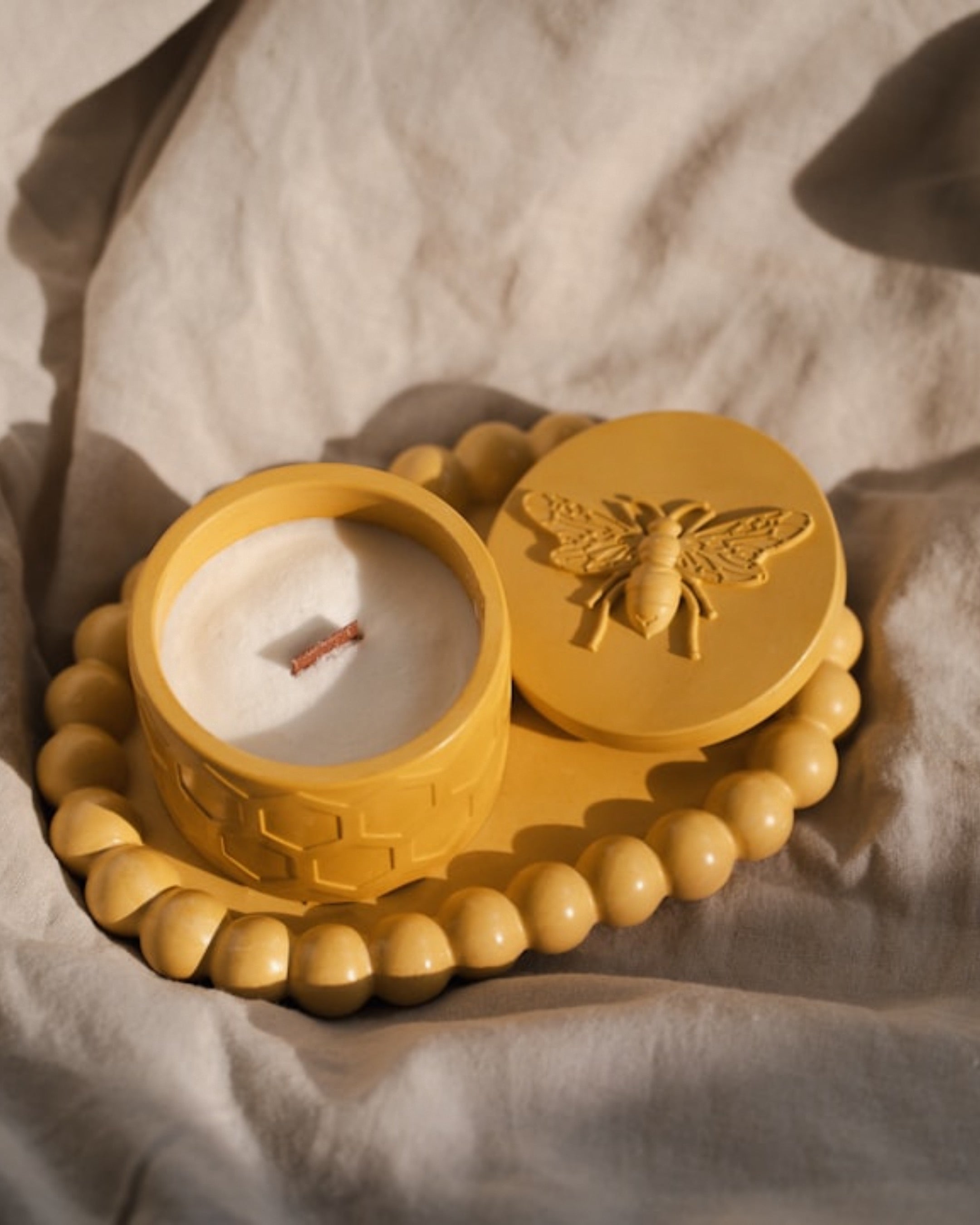 Image of a yellow candle embossed with a bee