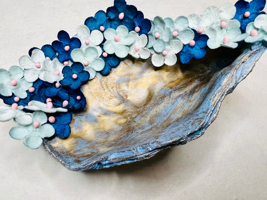 A blue painted oyster shell, with gilded gold details and blue ombre paper flowers.