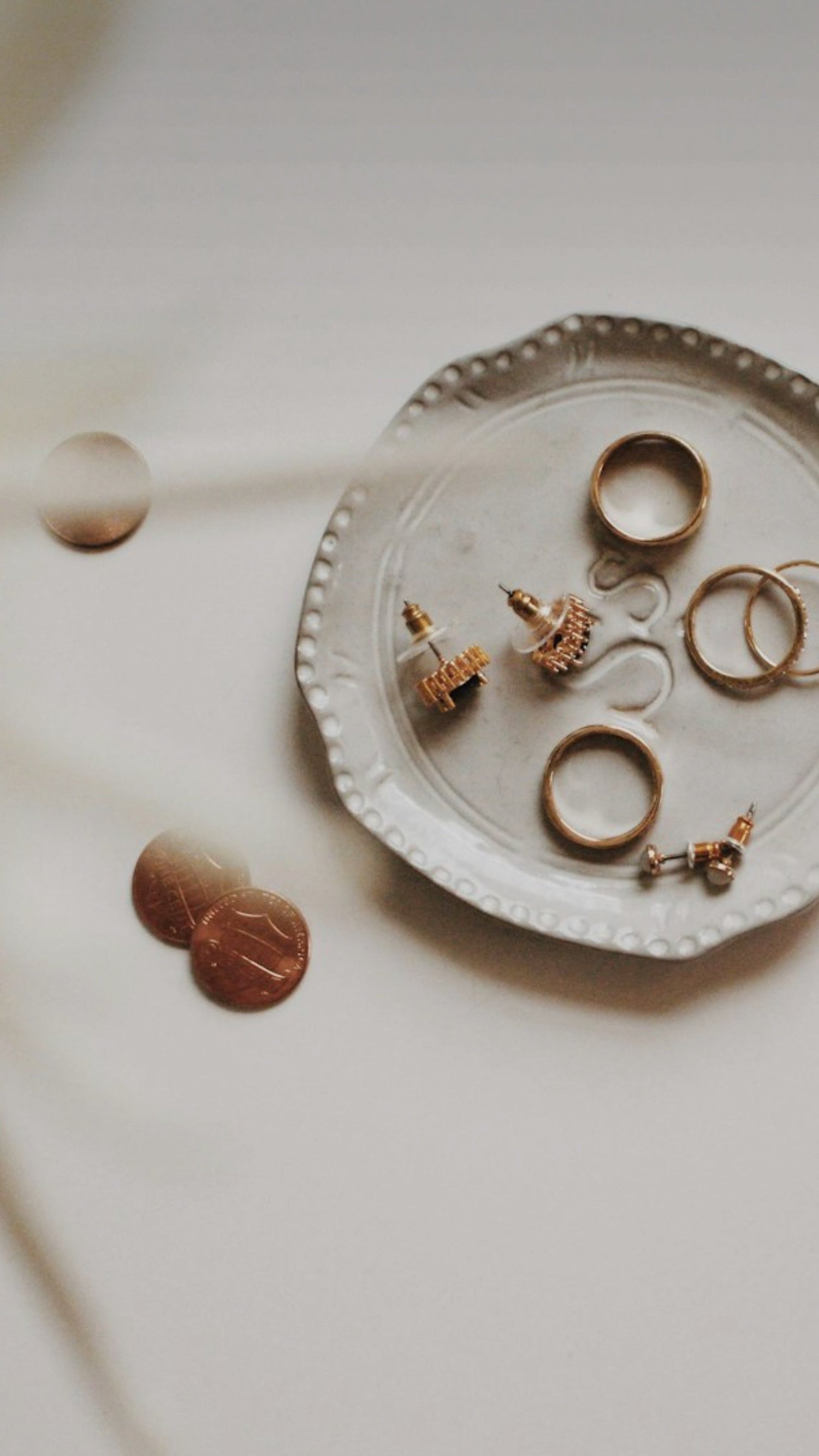 Image of jewelry pieces laying on a trinket dish with a white background